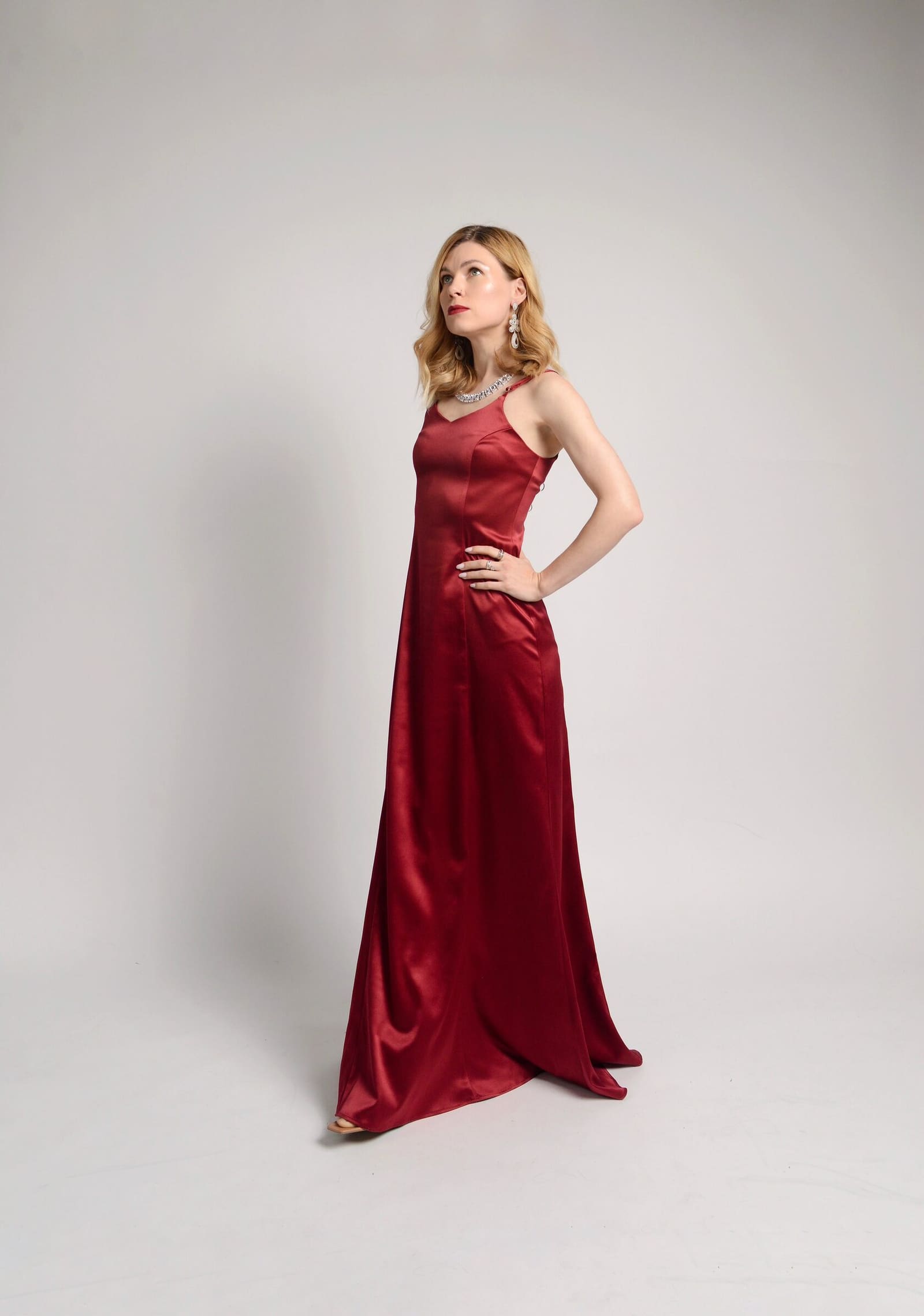A woman in a long red satin dress on a light backdrop