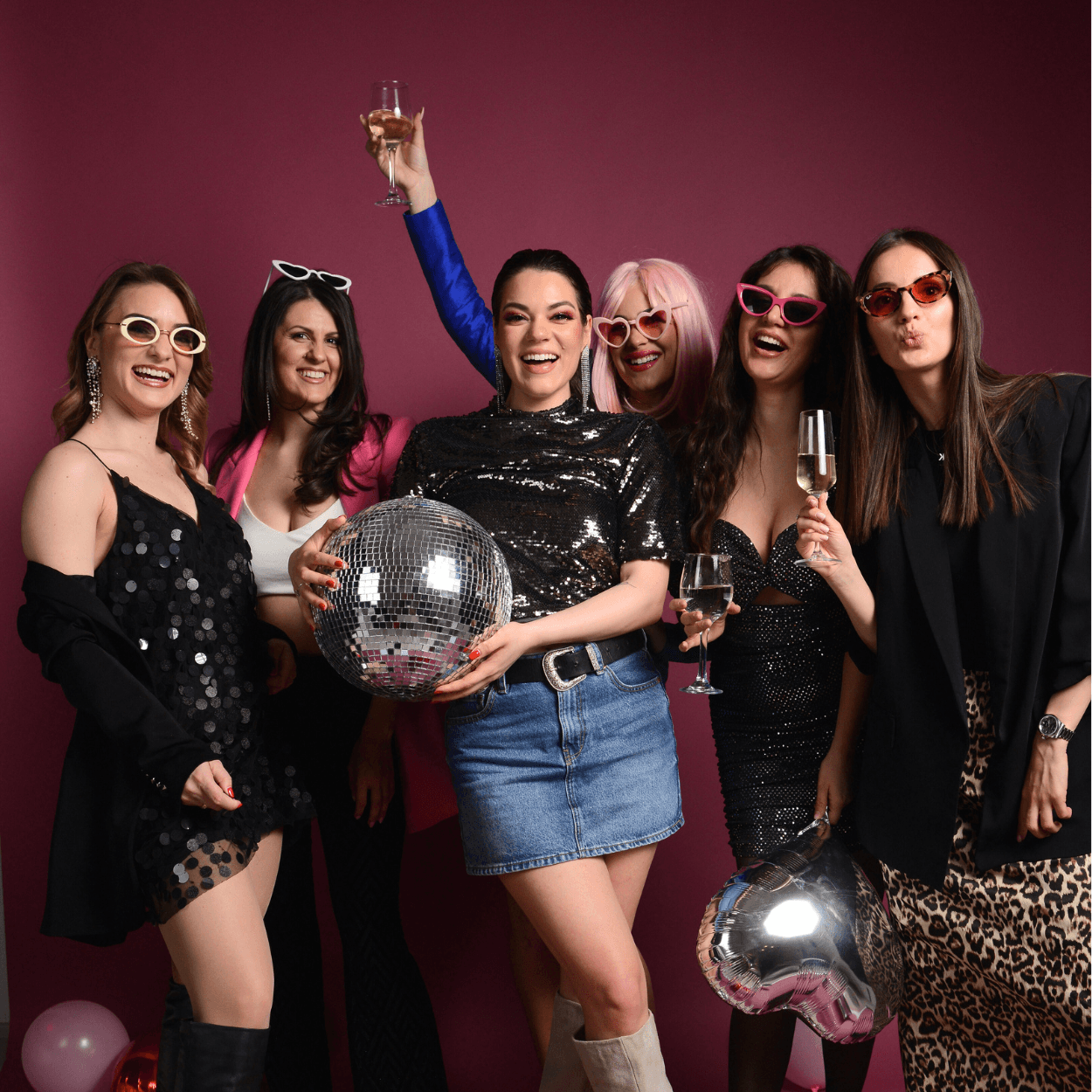 Šest drugarica sa disko kuglom, naočarima i šampanjcem na roze pozadini